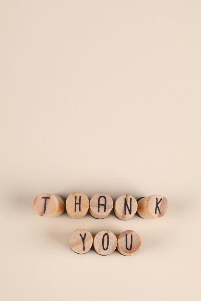 Minimalist wooden alphabet blocks spelling 'Thank You' on a neutral background.